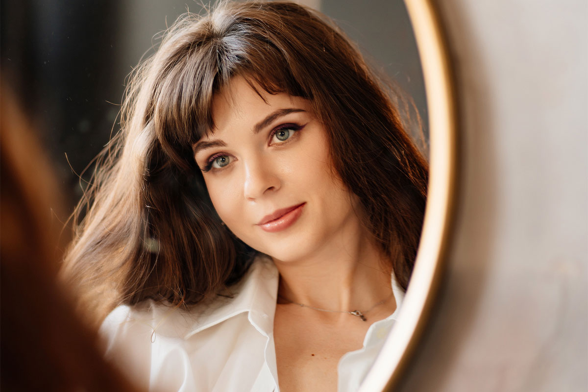 A woman looking in a mirror after BBL laser in Charlotte.